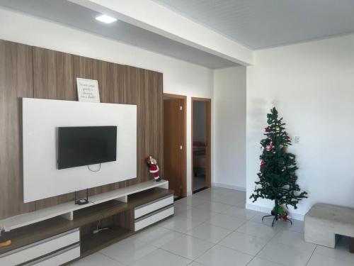 ein Wohnzimmer mit einem TV und einem Weihnachtsbaum in der Unterkunft CONDOMINIO MERIDIEN PRAIA MAR Praia do Abais in Estância