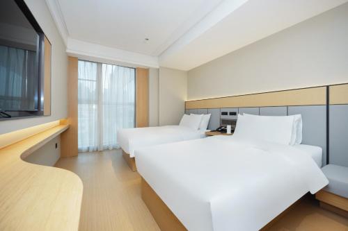 JI Hotel Shanghai Wujiaochang Changhai Hospital في شانغهاي: غرفة فندقية بسريرين وتلفزيون بشاشة مسطحة
