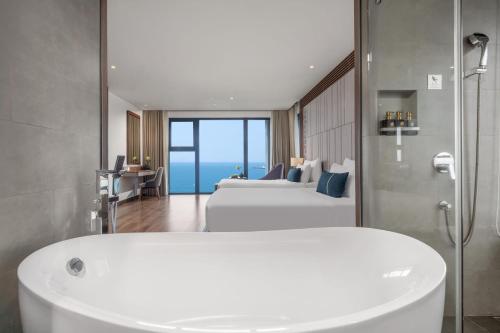 a bathroom with two beds and a tub in a room at Peninsula Hotel Danang in Da Nang