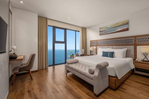 a bedroom with a large bed and a large window at Peninsula Hotel Danang in Da Nang
