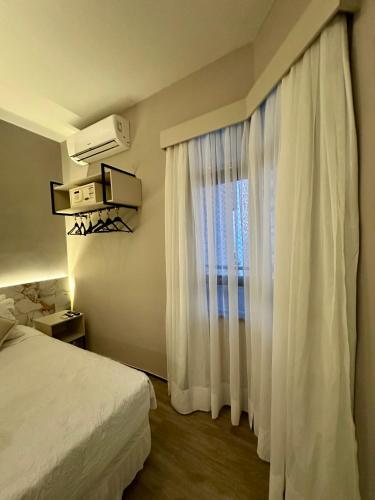 Schlafzimmer mit einem Bett und einem Fenster mit weißen Vorhängen in der Unterkunft 1155 golden 55m2 1 quarto frente mar avenida beira mar in Fortaleza