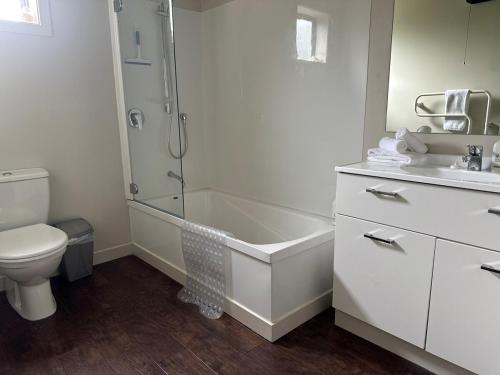 a bathroom with a tub and a toilet and a sink at Sunny Bob Lee Place in Wanaka