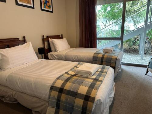 two beds sitting in a room with a window at Sunny Bob Lee Place in Wanaka