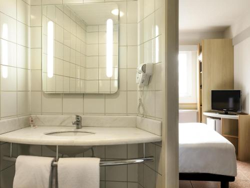 a bathroom with a sink and a mirror and a bed at ibis Criciuma in Criciúma