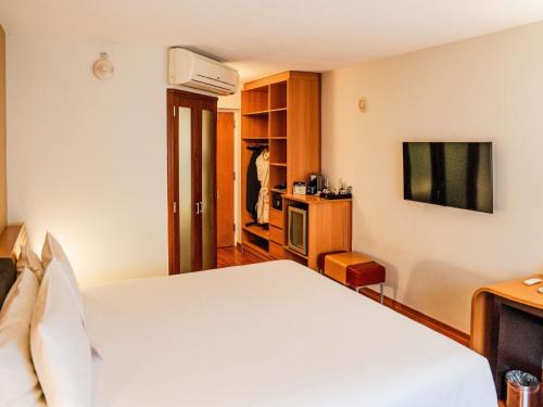 a bedroom with a white bed and a tv at Novotel Lima San Isidro in Lima