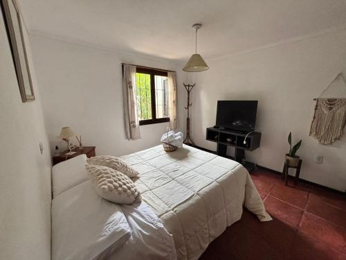 ein Schlafzimmer mit einem weißen Bett und einem Fernseher in der Unterkunft Cabaña LAS PALMAS dos dormitorios in Santa Clara del Mar