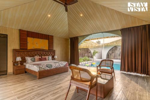 a bedroom with a bed and a table and a pool at StayVista at Rissaca Crown with Bonfire in Jaipur