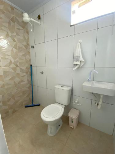 a white bathroom with a toilet and a sink at Casa do Pepe em Barra de Jacuípe in Camaçari
