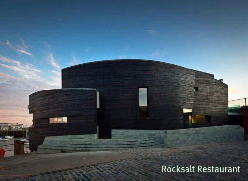 a black brick building with stairs in front of it at Rocksalt Rooms in Folkestone