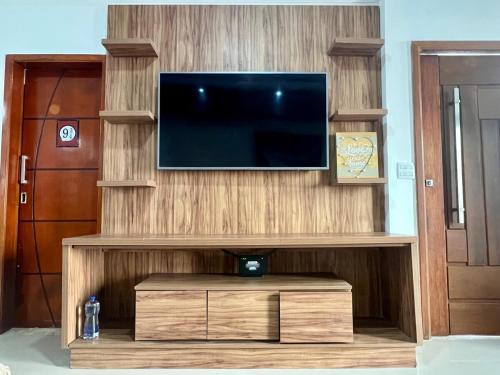 TV de pantalla plana en un centro de entretenimiento de madera en Casa aconchegante, en Río de Janeiro