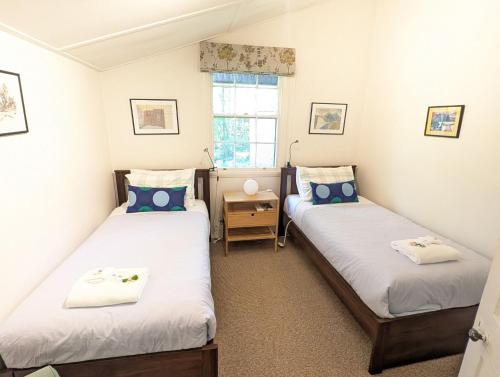 zwei Einzelbetten in einem Zimmer mit Fenster in der Unterkunft Redruth - 2 bedroom cottage situated in wandiligong in Wandiligong