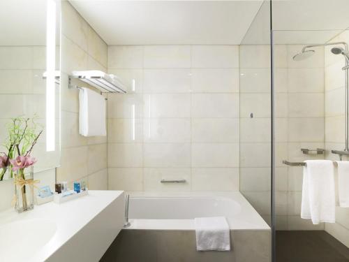 Un baño blanco con bañera y ducha. en Novotel Abu Dhabi Al Bustan, en Abu Dabi