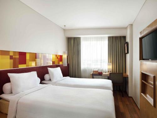 a hotel room with two beds and a flat screen tv at Ibis Styles Solo in Solo