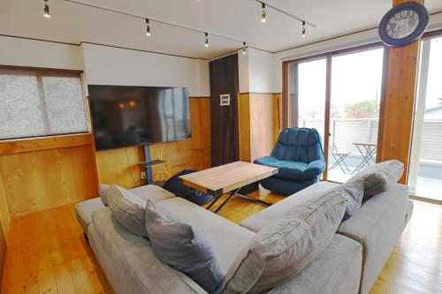 a living room with a couch and a table and a tv at Laina Minoh Makiochi in Minoo