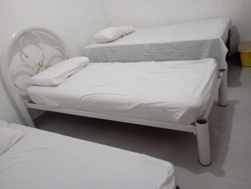 zwei Betten in einem Krankenhauszimmer mit weißen Laken in der Unterkunft Casa quase frente a Rodoviária in Corumbá