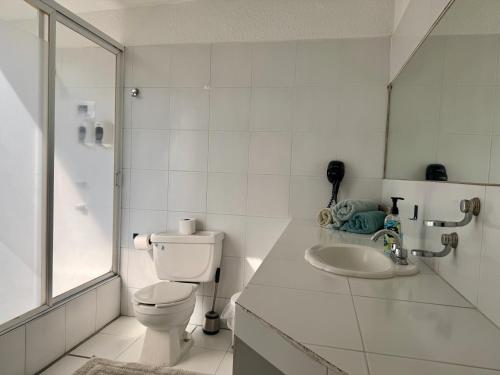Un baño blanco con inodoro y lavabo. en Casa con hermoso jardín y terraza, en Cuernavaca