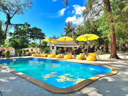 ein Schwimmbecken mit gelben Sonnenschirmen darauf in der Unterkunft Long Beach Club Krabi in Klong Muang Beach
