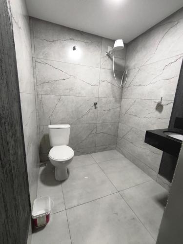 a bathroom with a white toilet and a shower at Lar Doce Lar Realizando Sono!!! in Arcos