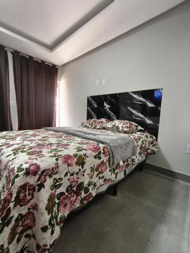 a bedroom with a bed with a floral comforter and a fireplace at Lar Doce Lar Realizando Sono!!! in Arcos