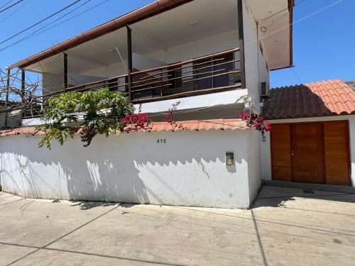 une maison blanche avec des plantes sur un mur dans l'établissement Casa Greemat 2Habs con AC, piscina a pasos de la playa, à Zorritos