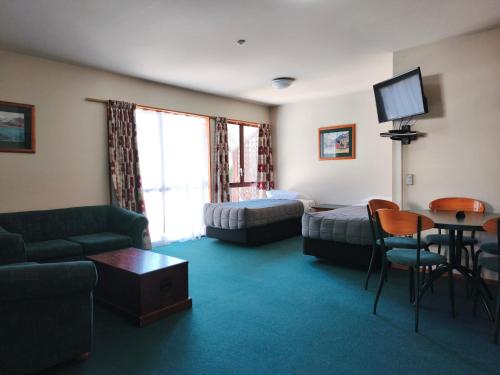 a hotel room with a couch and a bed and a tv at Aspen Lodge Motel in Hanmer Springs
