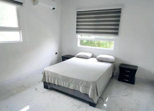 una camera da letto bianca con un letto e due finestre di Casa Bella Mansion a Nariño