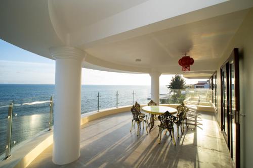 a balcony with a table and chairs and the ocean at Palado Hotel Mui Ne in Ấp Thiện Phước