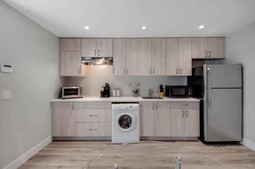 a kitchen with a refrigerator and a washing machine at Spacious 1BR Suite Near Capilano Bridge & Trails in North Vancouver