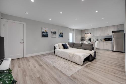 a white bedroom with a bed and a kitchen at Spacious 1BR Suite Near Capilano Bridge & Trails in North Vancouver