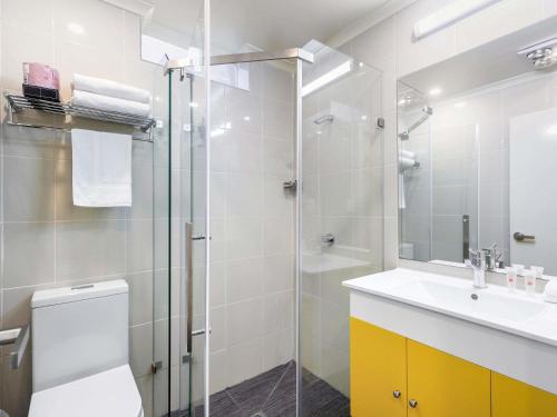 um banheiro com chuveiro, vaso sanitário e pia em ibis Styles Kingsgate Hotel em Melbourne