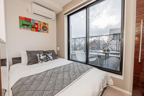 ein Schlafzimmer mit einem Bett und einem großen Fenster in der Unterkunft Mi-HOTEL SHIMOKITAZAWA in Tokio