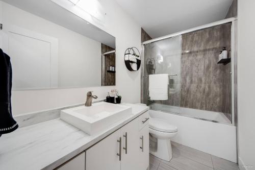 een witte badkamer met een wastafel en een toilet bij Modern 2Bed Suite Near Capilano Bridge & Trails in North Vancouver