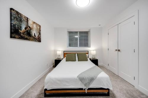 een witte slaapkamer met een bed en een schilderij aan de muur bij Modern 2Bed Suite Near Capilano Bridge & Trails in North Vancouver