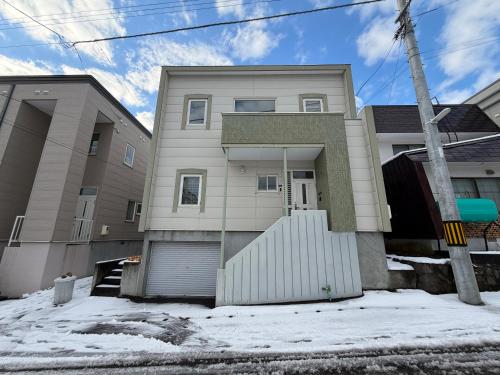 a house with a garage in the snow at 小樽の温もり一棟貸し in Otaru