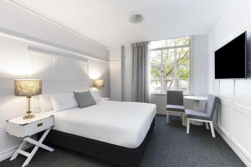 ブリスベンにあるアディナ アパートメント ホテル ブリスベン アンザック スクエアのベッドと机とテレビがあるホテルの部屋
