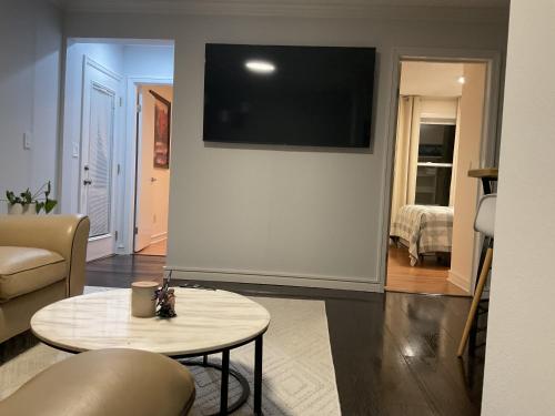 Una sala de estar con una mesa y un televisor en una pared. en Two fully independent unit - a modern house and a private apartment, each with its own entrance, located just 15 min from Sea-Tac Airport and 5 min from Des Moines Marina, en Des Moines