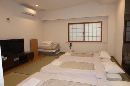a room with three beds and a flat screen tv at Park Hotel in Osaka