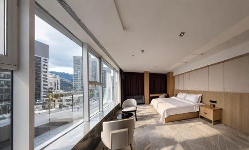 a hotel room with a bed and large windows at Paco Hotel Guangzhou Baiyun Airport Liantang Metro in Huadu