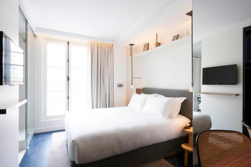 a hotel room with a white bed and a window at Perpetual Elysée Montaigne in Paris