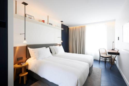 a hotel room with two beds and a table at Perpetual Elysée Montaigne in Paris
