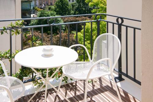 a white table and chairs on a balcony at Perpetual Elysée Montaigne in Paris