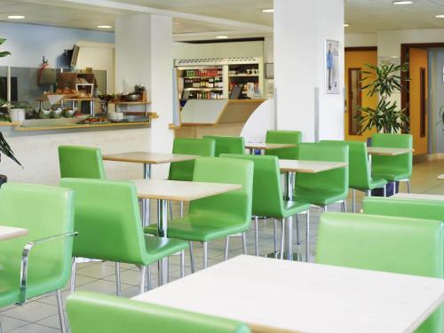 a cafeteria with tables and green chairs at ibis budget Newport in Newport