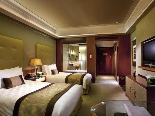 Una habitación de hotel con dos camas y un televisor. en Sofitel Harbin, en Harbin