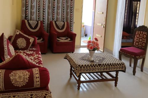 a living room with chairs and a table with a vase of flowers at Gardenia Inn in Madikeri