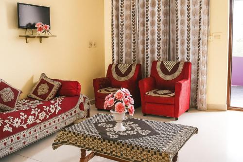 a living room with two red chairs and a table at Gardenia Inn in Madikeri