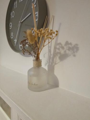 a white vase with flowers in it next to a clock at Story Haus apartments in Chester