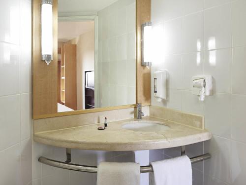 a bathroom with a sink with a mirror and towels at Ibis Merida in Mérida