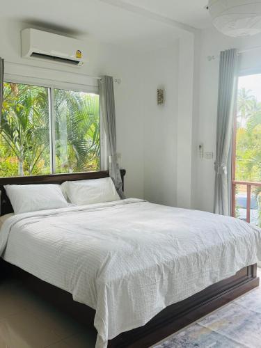 ein weißes Schlafzimmer mit einem großen Bett und einem Fenster in der Unterkunft Cozy Villa in the Tropical Garden in Ko Phangan