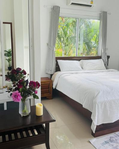 ein Schlafzimmer mit einem Bett und einem Fenster mit Blumen auf einem Tisch in der Unterkunft Cozy Villa in the Tropical Garden in Ko Phangan