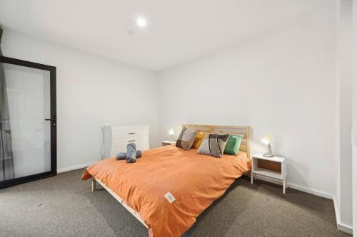 ein Schlafzimmer mit einem großen Bett mit einer orangefarbenen Tagesdecke in der Unterkunft Bright 1BR Apartment in the heart of Dickson in Downer